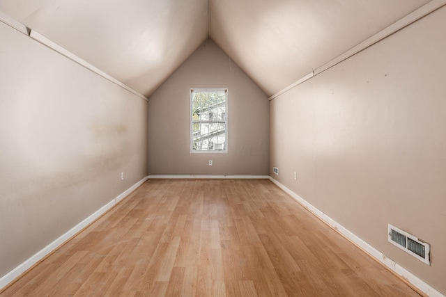 bonus room featuring light wood-style flooring, visible vents, vaulted ceiling, and baseboards