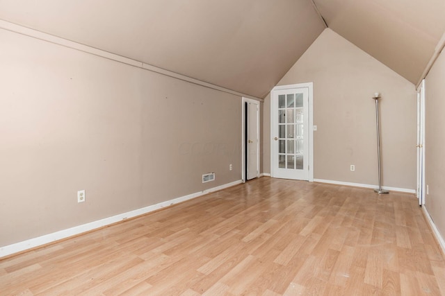 interior space with lofted ceiling, light wood-type flooring, visible vents, and baseboards