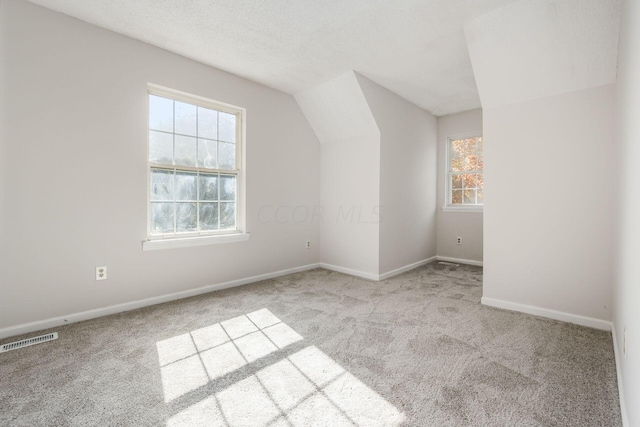 bonus room featuring a healthy amount of sunlight, carpet floors, visible vents, and vaulted ceiling