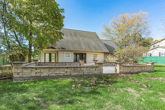 rear view of property featuring a yard, roof with shingles, fence, and a patio