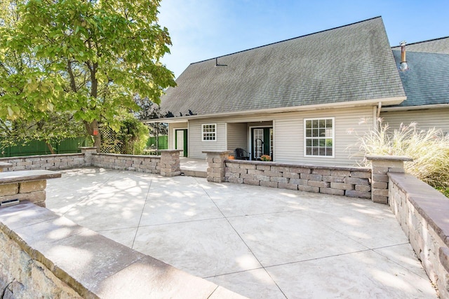 exterior space featuring a shingled roof and a patio