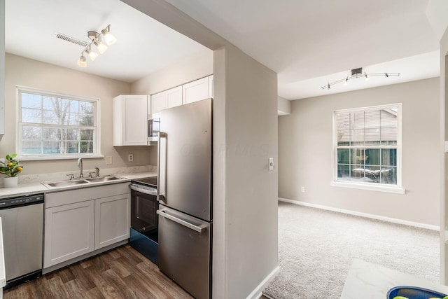 kitchen featuring baseboards, appliances with stainless steel finishes, light countertops, white cabinetry, and a sink