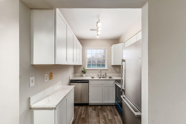 kitchen featuring white cabinets, dark wood-style flooring, rail lighting, stainless steel appliances, and a sink