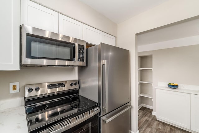 kitchen featuring light stone counters, wood finished floors, white cabinetry, baseboards, and appliances with stainless steel finishes