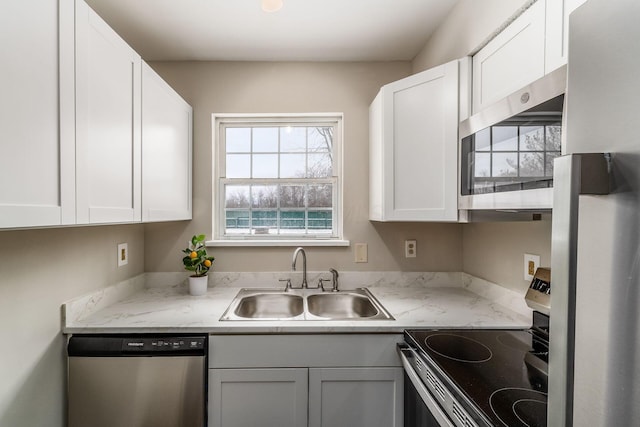 kitchen featuring appliances with stainless steel finishes, white cabinets, and a sink