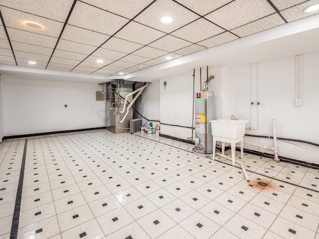 basement featuring heating unit, a drop ceiling, sink, and water heater