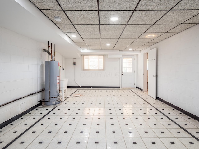 basement with a paneled ceiling and gas water heater