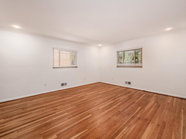 unfurnished room with a healthy amount of sunlight, wood-type flooring, and crown molding