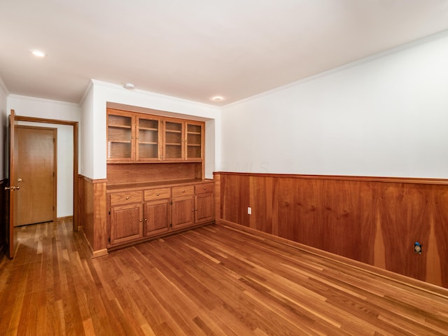 spare room featuring wooden walls, built in features, ornamental molding, and hardwood / wood-style flooring