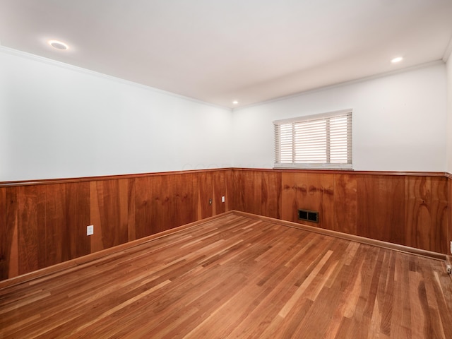 spare room with hardwood / wood-style floors, ornamental molding, and wood walls