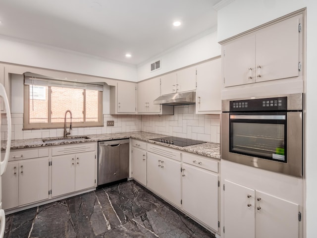 kitchen with backsplash, sink, appliances with stainless steel finishes, light stone counters, and white cabinetry