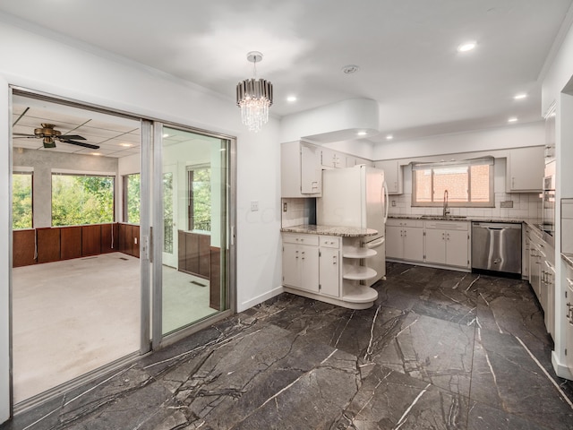 kitchen with tasteful backsplash, sink, pendant lighting, dishwasher, and white cabinetry