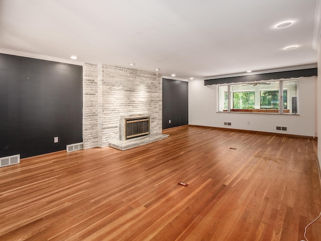 unfurnished living room with hardwood / wood-style flooring, crown molding, and a fireplace