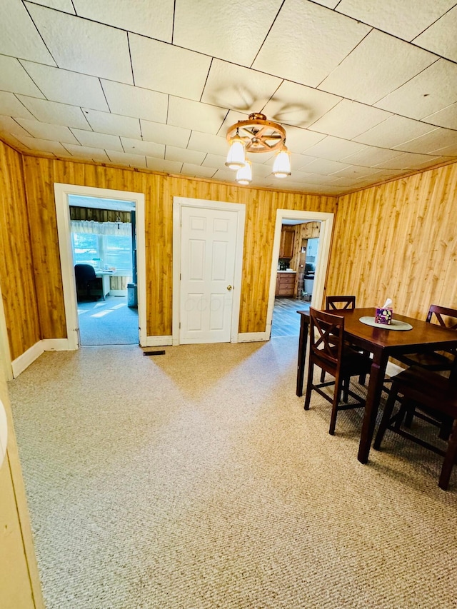 dining space with carpet flooring and wood walls