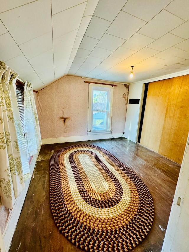 bonus room with wooden walls, dark wood-type flooring, and lofted ceiling