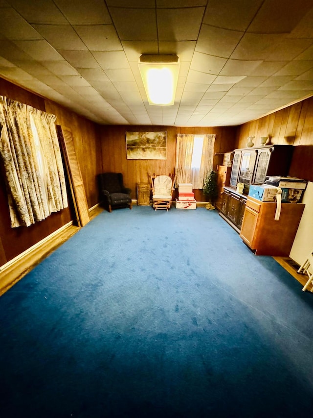 unfurnished room featuring carpet flooring and wood walls