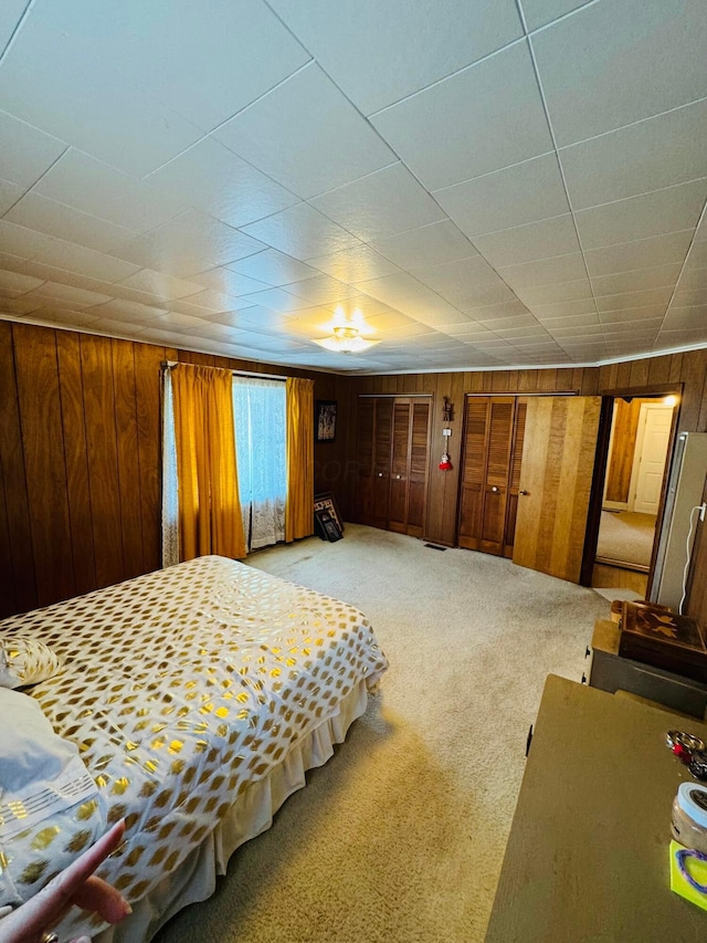 carpeted bedroom featuring stainless steel fridge and wooden walls