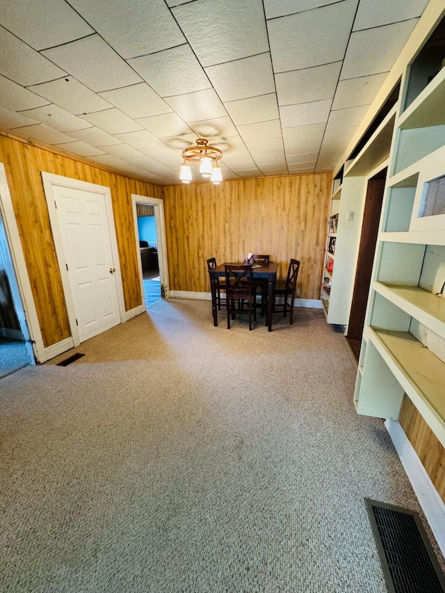 carpeted dining area featuring ceiling fan and wood walls