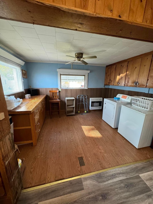 clothes washing area with heating unit, plenty of natural light, washer and dryer, and wood-type flooring