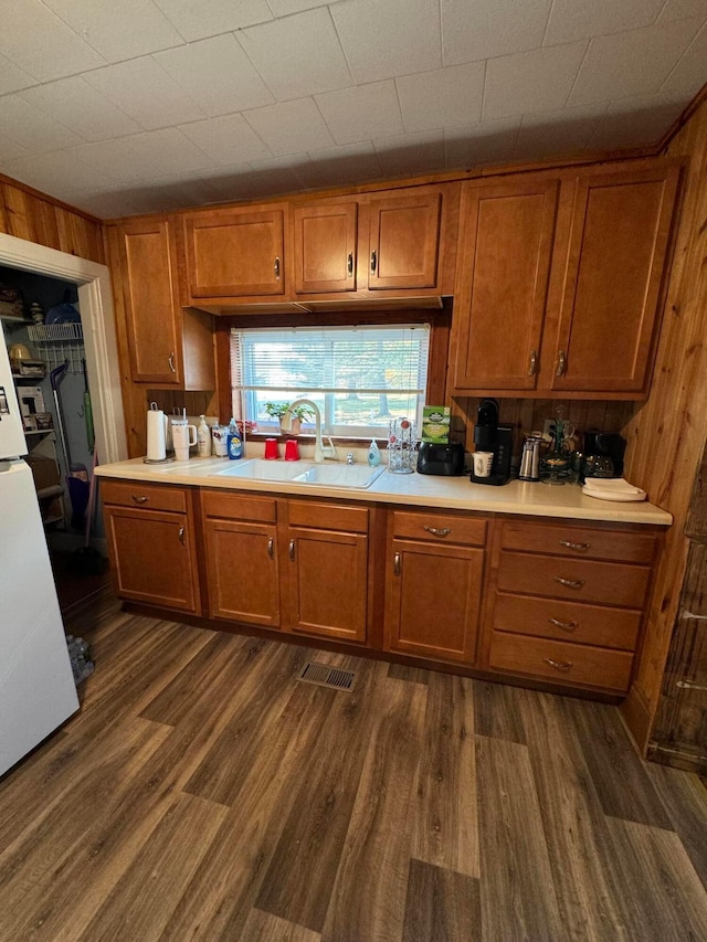 kitchen featuring dark hardwood / wood-style floors, wood walls, and sink