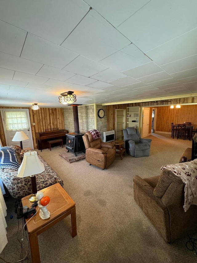 living room with carpet flooring, a wood stove, and wooden walls