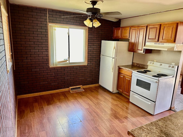 kitchen with white appliances, ceiling fan, light wood-type flooring, light stone counters, and brick wall