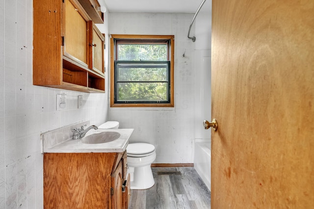 full bathroom with bathtub / shower combination, hardwood / wood-style floors, toilet, vanity, and tile walls