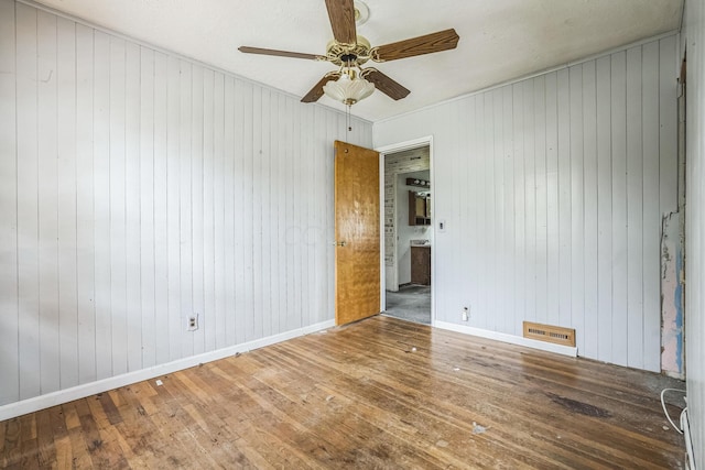 spare room featuring hardwood / wood-style flooring, ceiling fan, and wood walls