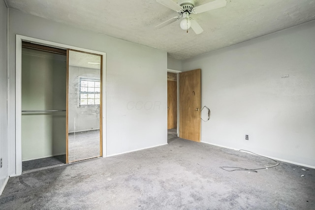 unfurnished bedroom with ceiling fan, a closet, a textured ceiling, and dark colored carpet