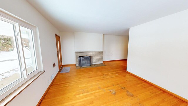 unfurnished living room with visible vents, light wood-style flooring, a fireplace, and baseboards