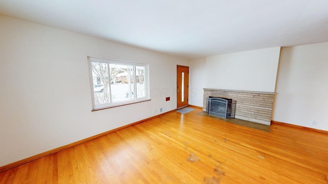 unfurnished living room featuring light wood-style flooring, a fireplace, and baseboards