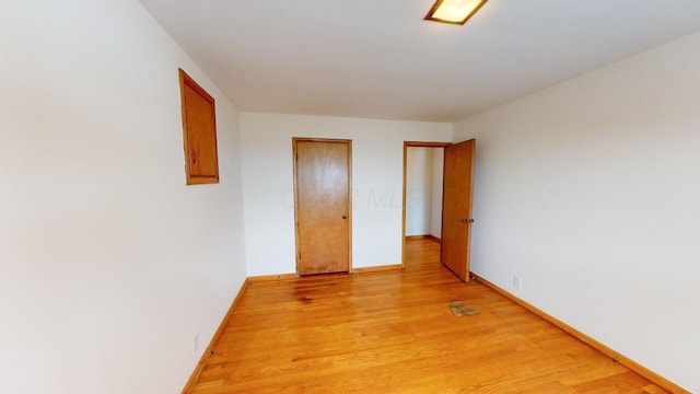 spare room with baseboards and light wood-style floors