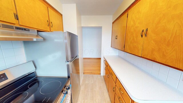 kitchen with under cabinet range hood, backsplash, stainless steel electric stove, and light countertops