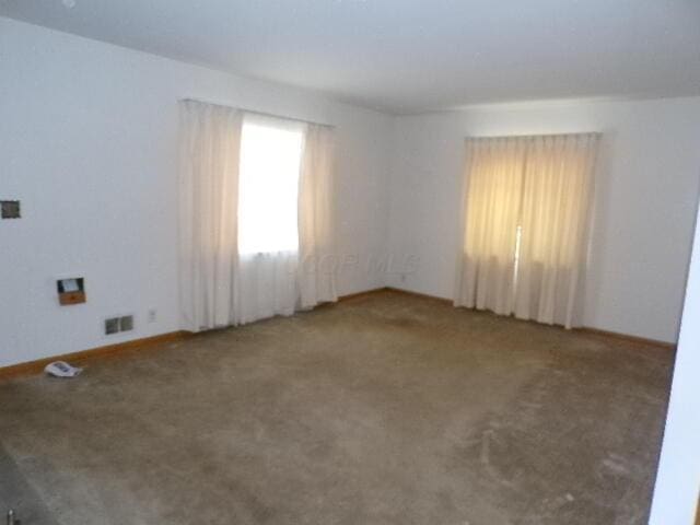 carpeted spare room featuring visible vents