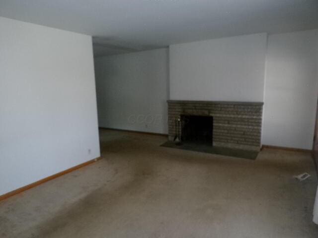 unfurnished living room featuring carpet flooring, baseboards, and a fireplace