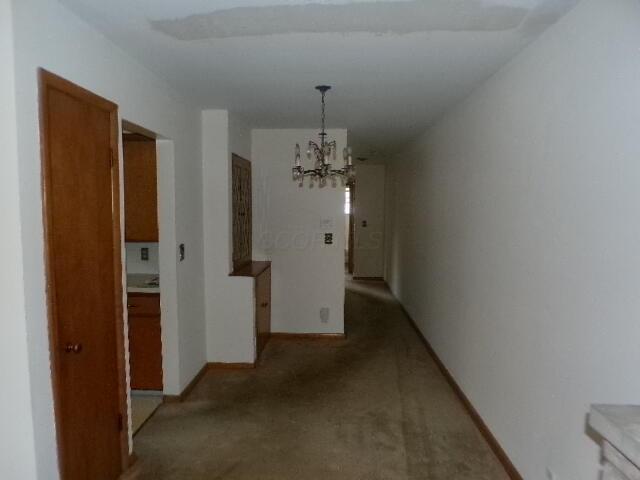 corridor with a notable chandelier and baseboards