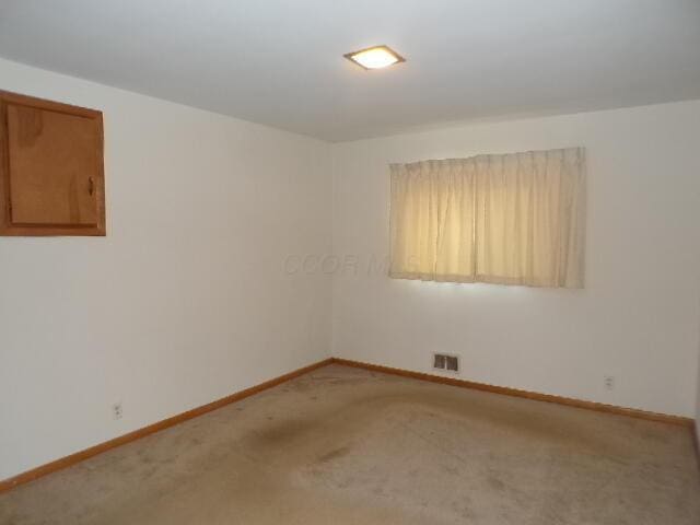 empty room featuring light carpet, visible vents, and baseboards