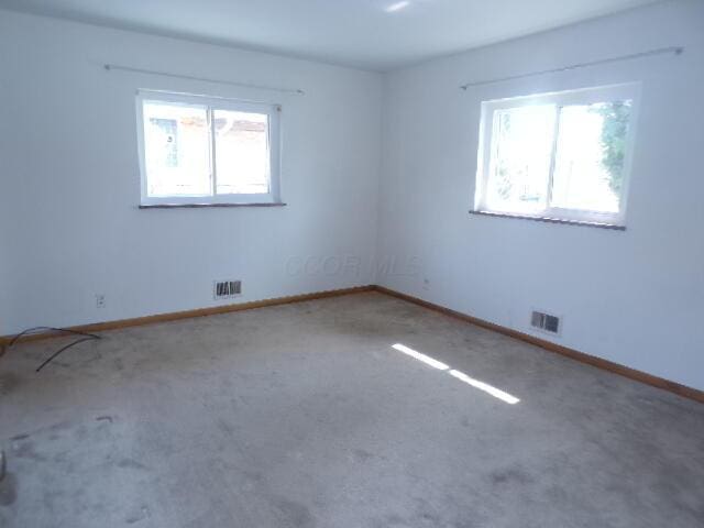 carpeted spare room with baseboards and visible vents