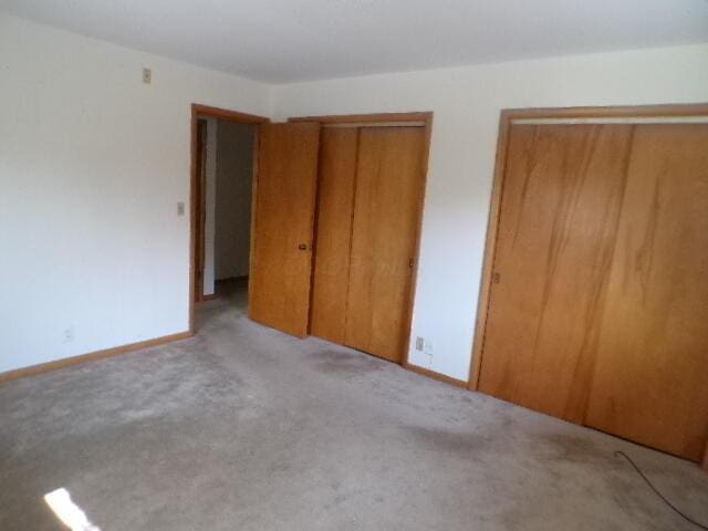 unfurnished bedroom with baseboards and multiple closets