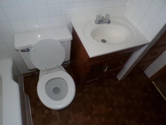 bathroom with tile walls, toilet, and vanity