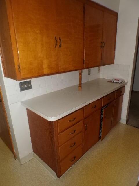 kitchen featuring decorative backsplash, brown cabinets, and light countertops