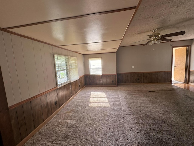 carpeted spare room with ceiling fan and wooden walls