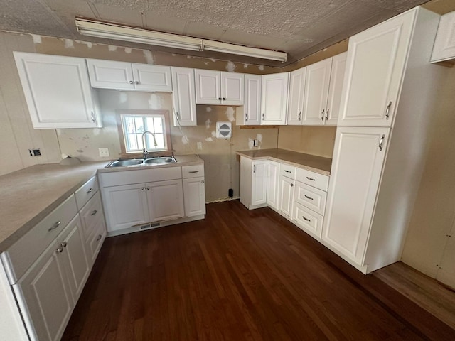 kitchen featuring white cabinets, dark hardwood / wood-style flooring, sink, and a textured ceiling