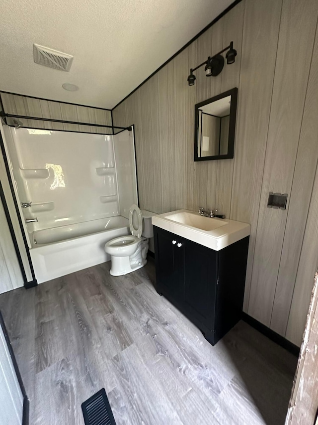 full bathroom with hardwood / wood-style floors, tub / shower combination, a textured ceiling, and toilet