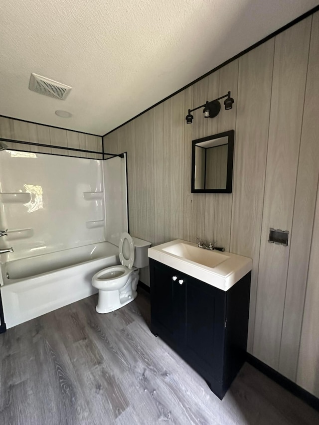 full bathroom with hardwood / wood-style floors, a textured ceiling, toilet, vanity, and shower / bathtub combination