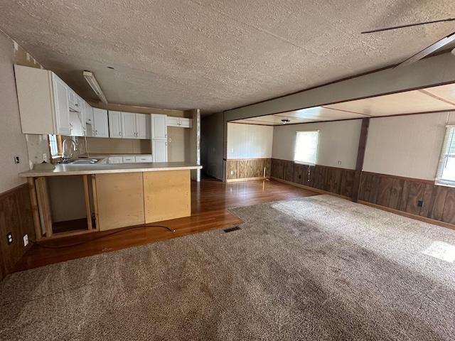 8565 Smith Calhoun Rd Unit 162, Plain City, OH 43064 - kitchen featuring dark colored carpet, a textured ceiling, a peninsula, wood walls, and open floor plan