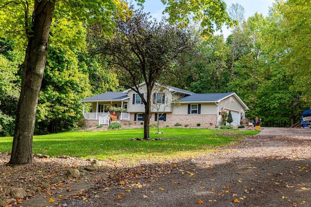 split level home featuring a porch, a front lawn, and a garage