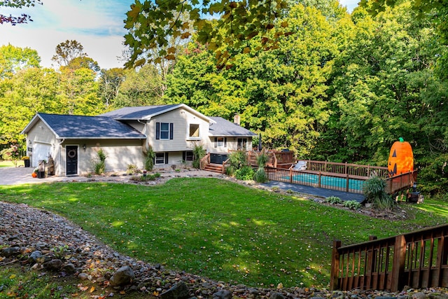 exterior space featuring a garage, a pool side deck, and a lawn