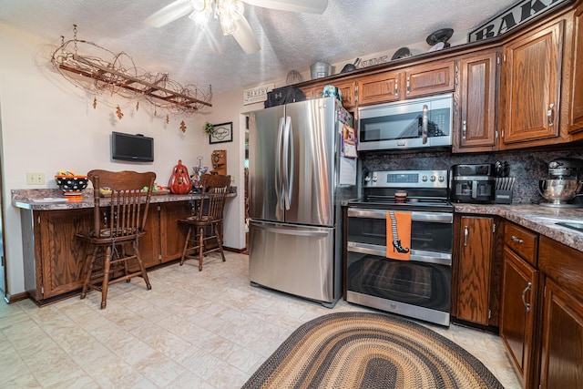 kitchen with a textured ceiling, stainless steel appliances, backsplash, and ceiling fan