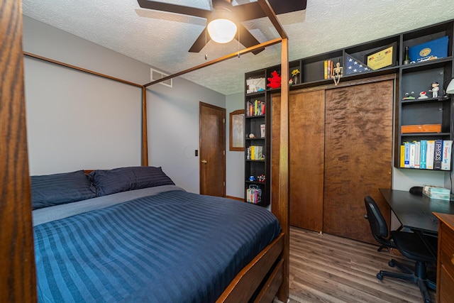 bedroom featuring a textured ceiling, wood-type flooring, ceiling fan, and a closet